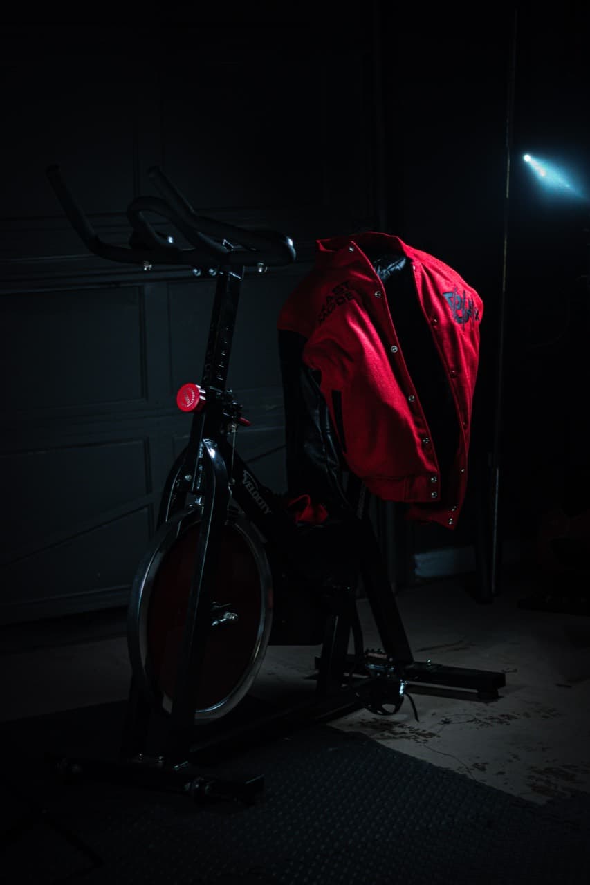 Dark product scene with a stationary bike and red Beast Mode jacket
