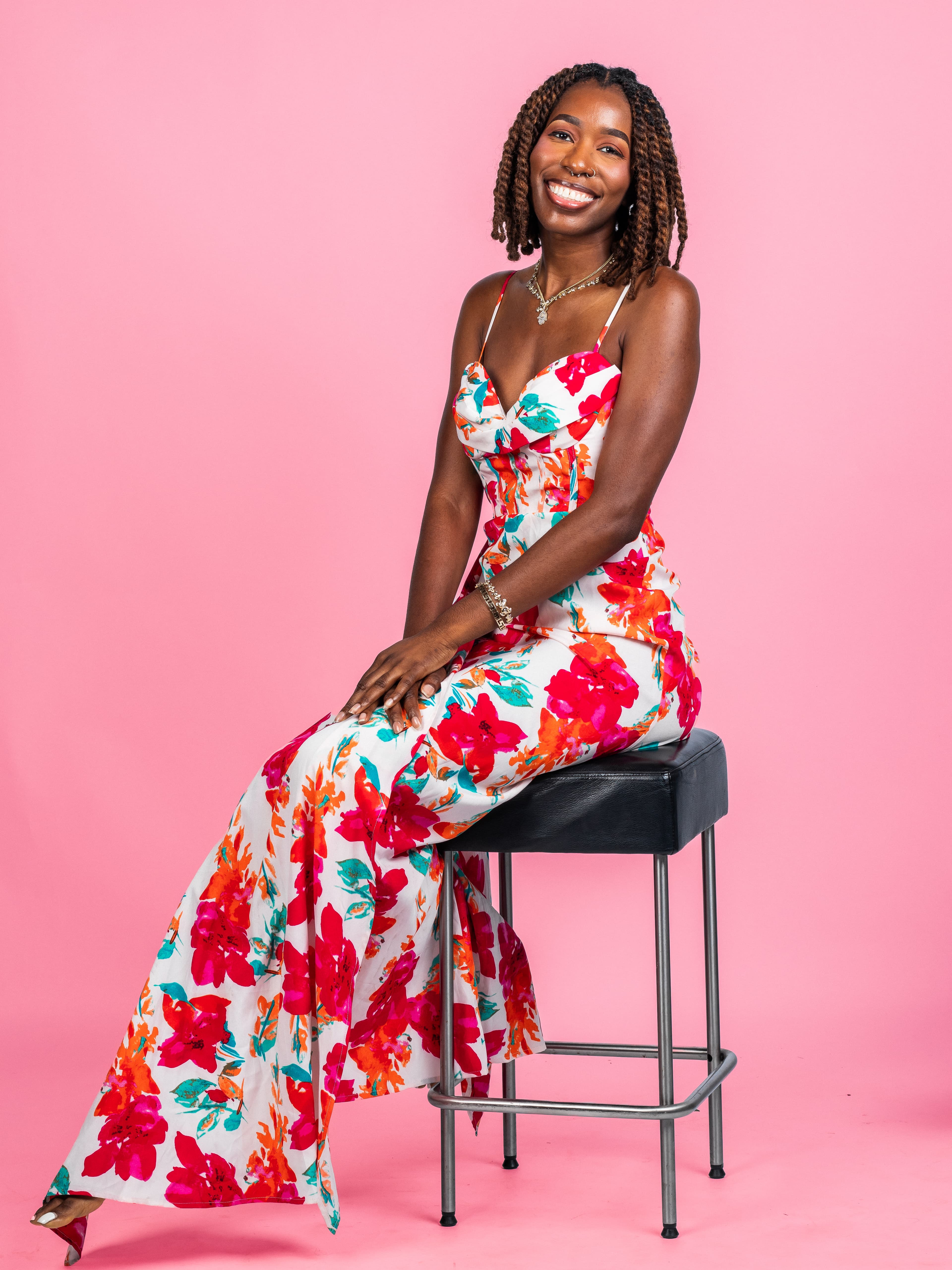 Studio portrait of a woman seated against a pink backdrop